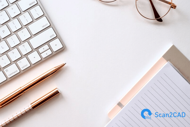 Desk with notepad, pens, glasses and computer keyboard