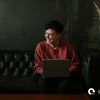 person with a laptop, smiling on a sofa